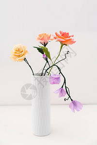 白色花瓶中的绉纸玫瑰和甜豌豆花束图片