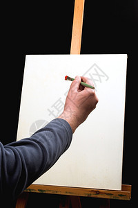 帆布手用画笔和画架在黑色背景图片