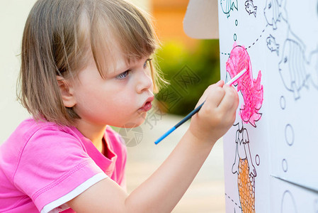 在花园里画纸板屋的小女孩背景图片