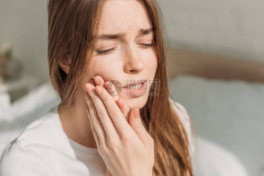 年轻妇女在牙痛时触摸脸颊同时图片
