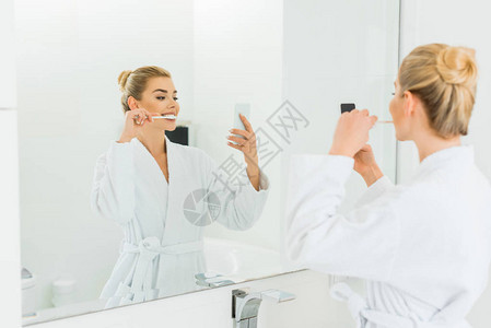 白浴袍刷牙和洗手间自拍的漂亮女人有选择图片