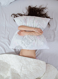 女孩睡在家里的一张白色床上年轻女子穿着睡衣在家里床上的白色床背景图片