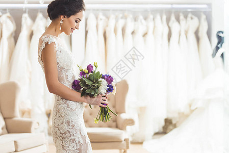 迷人的新娘在婚礼时装店看花束图片