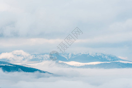 白色蓬松的云彩中的雪山美景图片