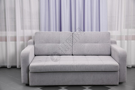 灰色沙发靠在房间的窗帘上图片