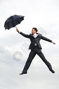 商人在天空背景上手持雨伞在空中自图片