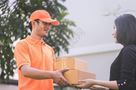 穿橙色衣服的快递员正在给一个女人递包裹图片