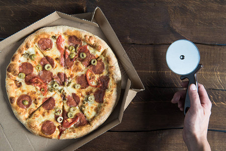 在纸板盒和人手披萨切饼机中最美味背景图片