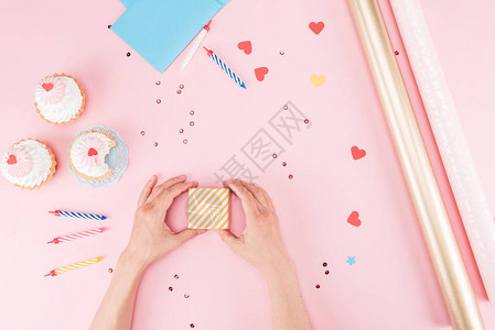 粉红色生日派对概念上手包礼盒和美味纸杯蛋糕图片