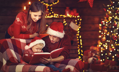 圣诞快乐爸和孩子在圣诞节树旁读书的亲图片