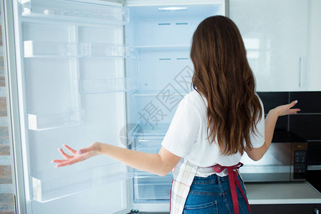 隔离期间厨房里的年轻女子看上面没有的空冰箱架子饿了不会做饭女人的背影不背景图片