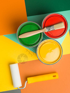 三罐黄绿色和红色油漆刷子和彩色几图片