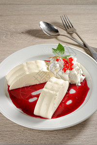 白盘上的红醋栗酱意式奶冻图片
