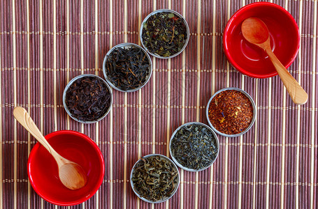 黑茶绿茶和红碗中的木勺子放在棕竹子垫上图片