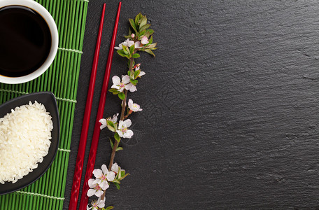 黑石背景上的日本寿司筷子酱油碗米饭和樱花图片