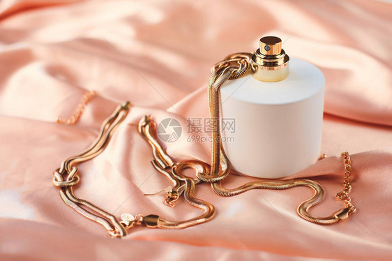 粉红色背景中带金项链的香水瓶图片