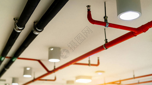 自动消防喷淋系统和黑水冷却供应管灭防和探测器带有红色管道的消防喷淋系统悬挂在建筑物背景图片