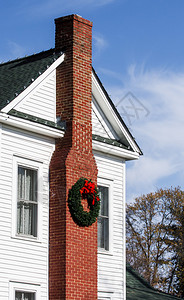ChirstmasWreath与红弓搭配在旧的白色侧边传统农舍图片