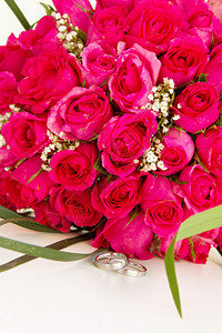 红玫瑰的结婚戒指和新娘花束图片