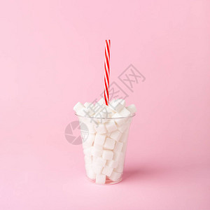 粉色面糊底片上装满糖块的塑料杯不健康的食品概念最小垂图片