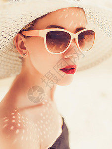 穿着大帽子和墨镜的年轻美女在海滩图片