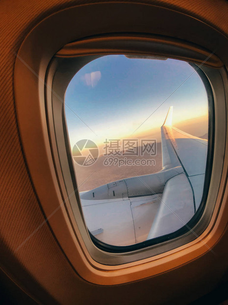 透过飞机窗口窗框云层上方机翼和云的可见部分概念图片