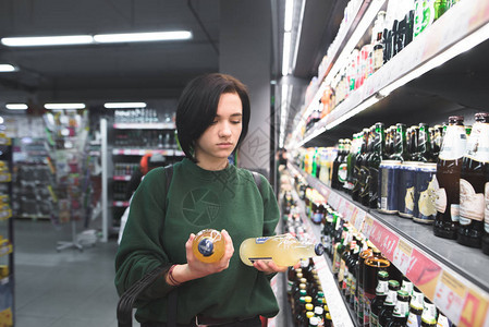 超市里女人看着手中的啤酒图片
