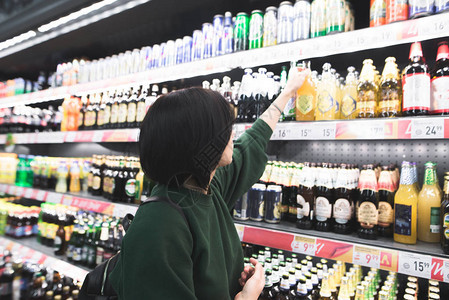 女人在超市货架上挑选啤酒图片