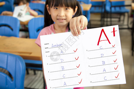 微笑的小女孩在课堂上展示考试成绩图片