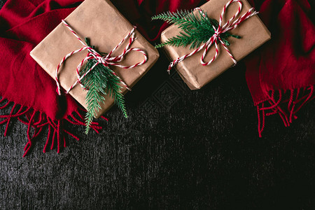 以棕色纸包裹的礼品包顶端视图和黑色背景上的红色围巾图片