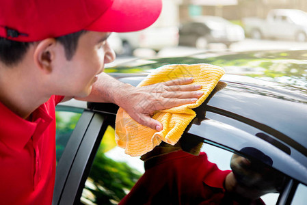 红色制服清洁车的汽车服务人员用超细纤维布汽车细图片