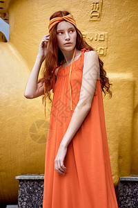 红发时装模型以橙色裙子和烟斗附近的图片
