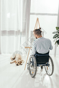 坐在轮椅上的残疾人在家窗前画而他的图片