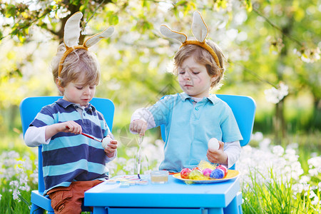 复活节兔子耳朵里的两个小兄弟在春天花园里背景图片
