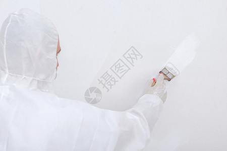 工人穿着工作服把墙漆成白色图片