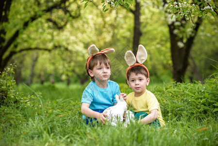 两个小男孩和朋友在春天花园的传统寻蛋活动中背景图片