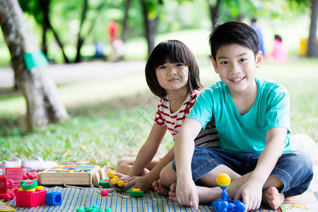 亚洲兄弟姊妹在公园玩得开心有两个快乐的孩子坐在绿草地上图片