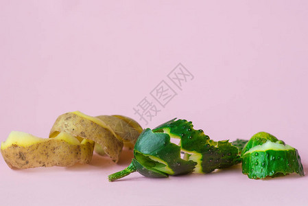粉红背景的黄瓜和马铃薯皮作为回收循图片