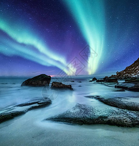 挪威罗弗敦群岛上的北极光海洋岸上方的绿色北极光与极光的夜空夜间冬季景观与极光和水面上的反射挪图片