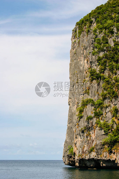 海洋中巨大而巨大的岩石有绿色森林和棕榈树的小岛蓝天白云在靠近kophi图片