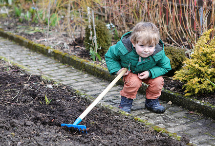 春天的小男孩带着花园锄头在户外图片