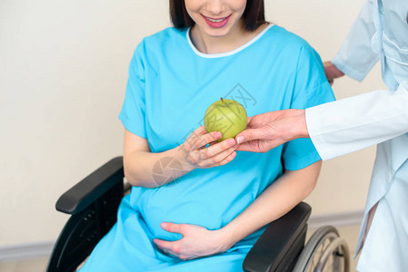 产科妇产科医生给轮椅孕妇以绿苹果拍摄的青图片