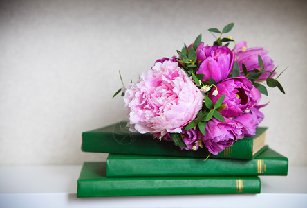 绿色书籍上粉色牡丹郁金香和铃兰的婚礼花束图片