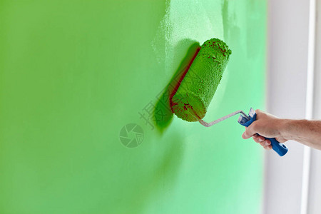 带油漆滚筒的男手绘墙粉刷公寓用图片