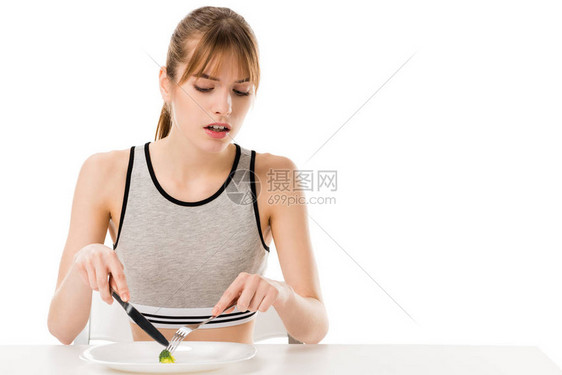 恶心的瘦女人吃一块花椰菜从盘子图片