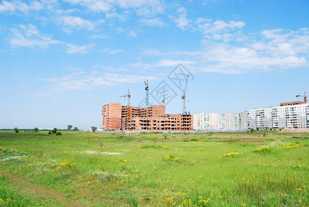 正在建造的住宅建筑和四架起重机与绿的天空对冲图片