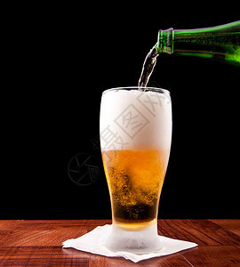 瓶装啤酒倒进一个冷藏的玻璃杯里孤立图片