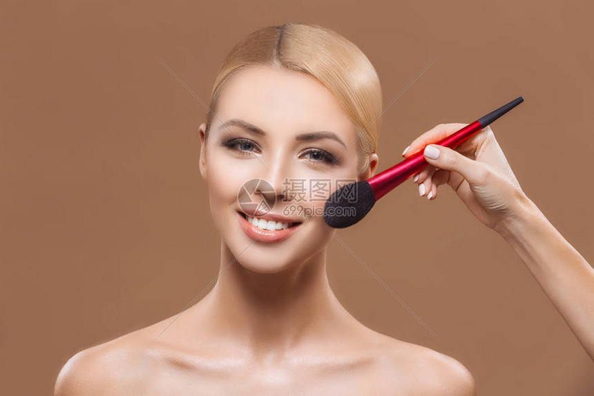 美貌丽的女人施粉和化妆刷在棕图片