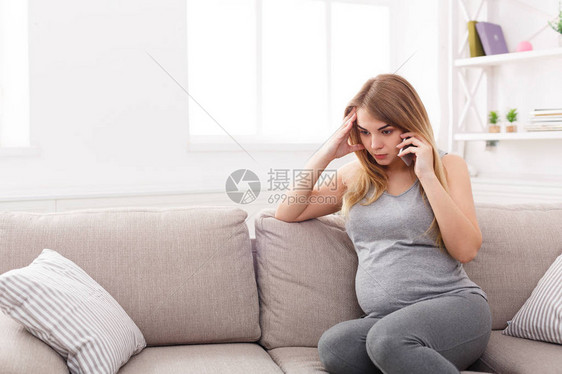 担心的孕妇通电话悲伤的期待金发女郎与她的医生认真交谈医疗保健咨询怀孕问图片