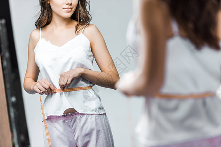 测量腰线和照镜子的妇女的作图片